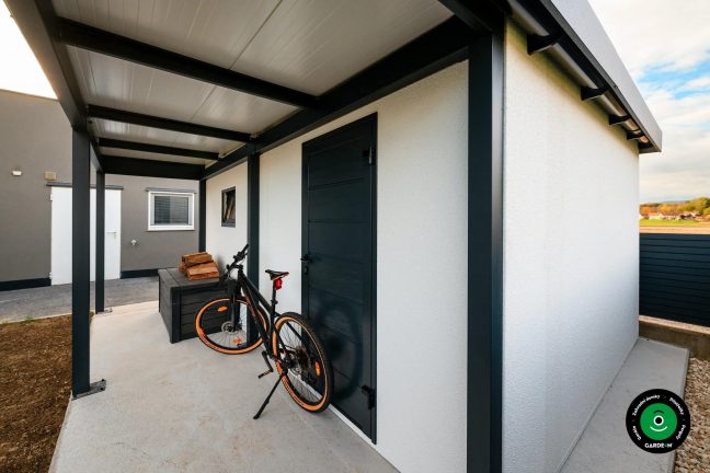 Přístřešek u garáže s kolem opřeným o stěnu