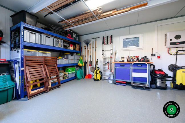 Zahradní nářadí uspořádané u modrých policových regálů